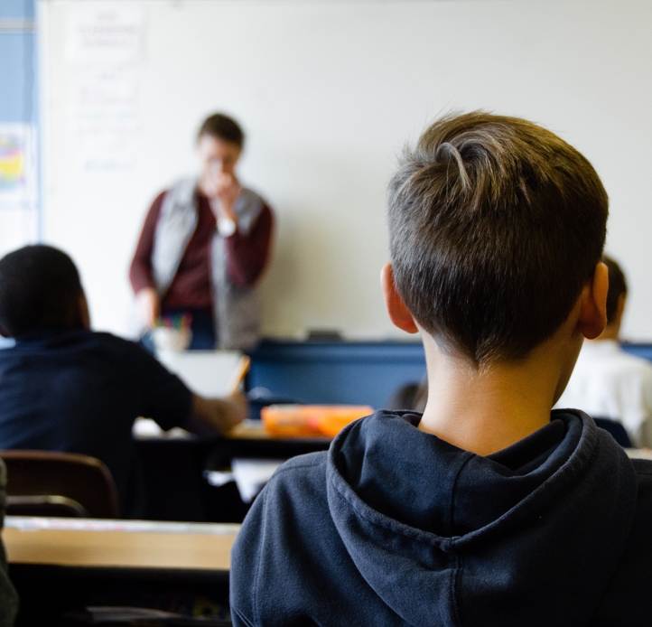 Students in classroom, teacher at front of room at whiteboard